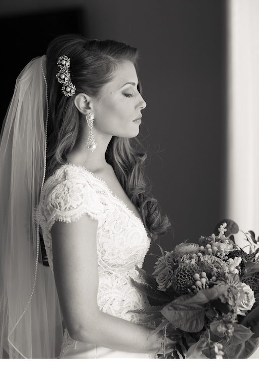 bride wearing lace-wedding-dress pearls holding bouquet